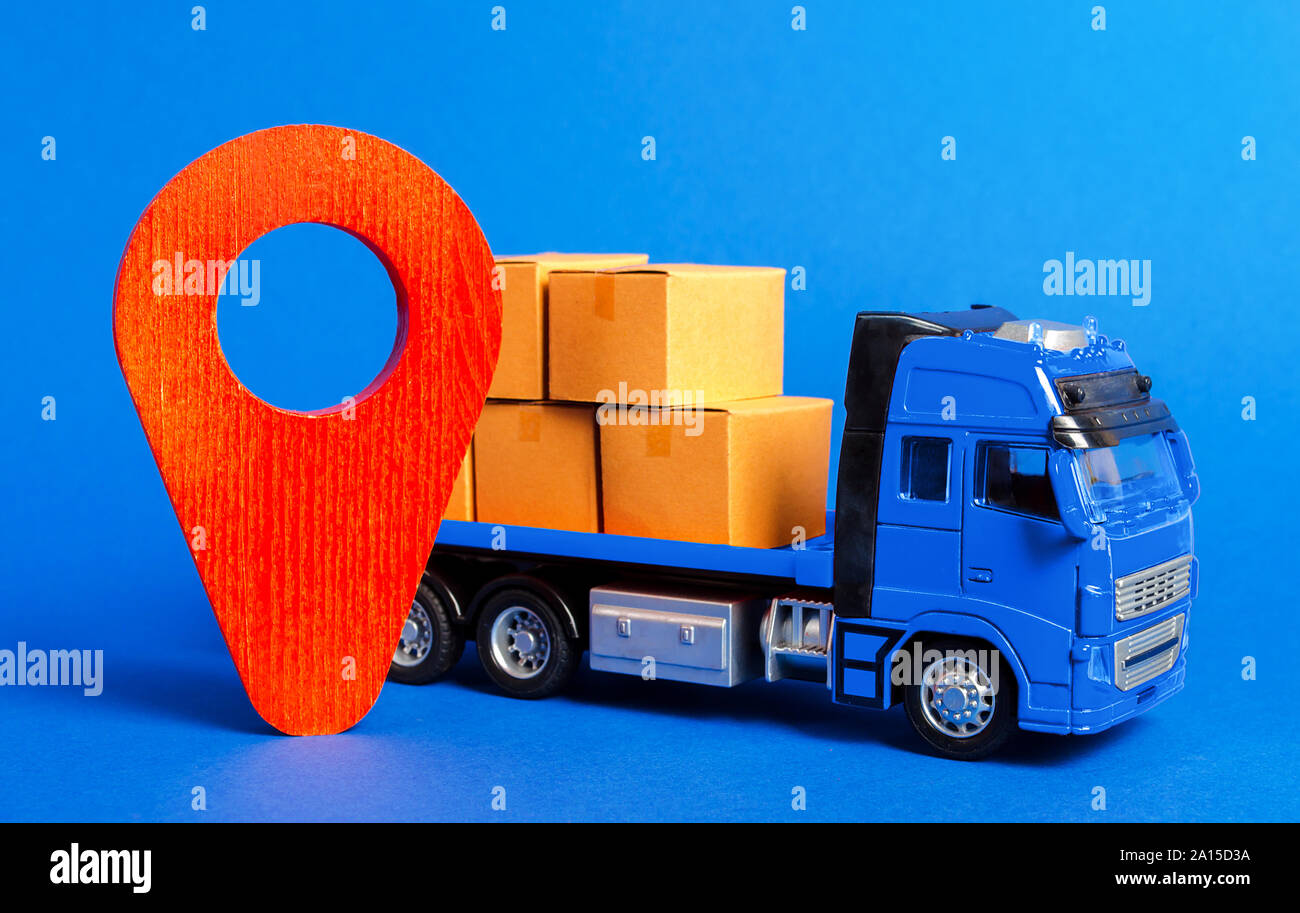 A blue truck loaded with boxes and a red pointer location. Services transportation of goods, products, logistics and infrastructure. Transportation co Stock Photo