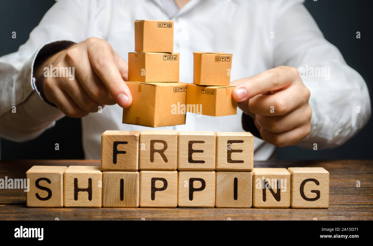A man holds boxes over the inscription free shipping. Transportation of goods and services, distribution and delivery of orders. Promotions preferenti Stock Photo