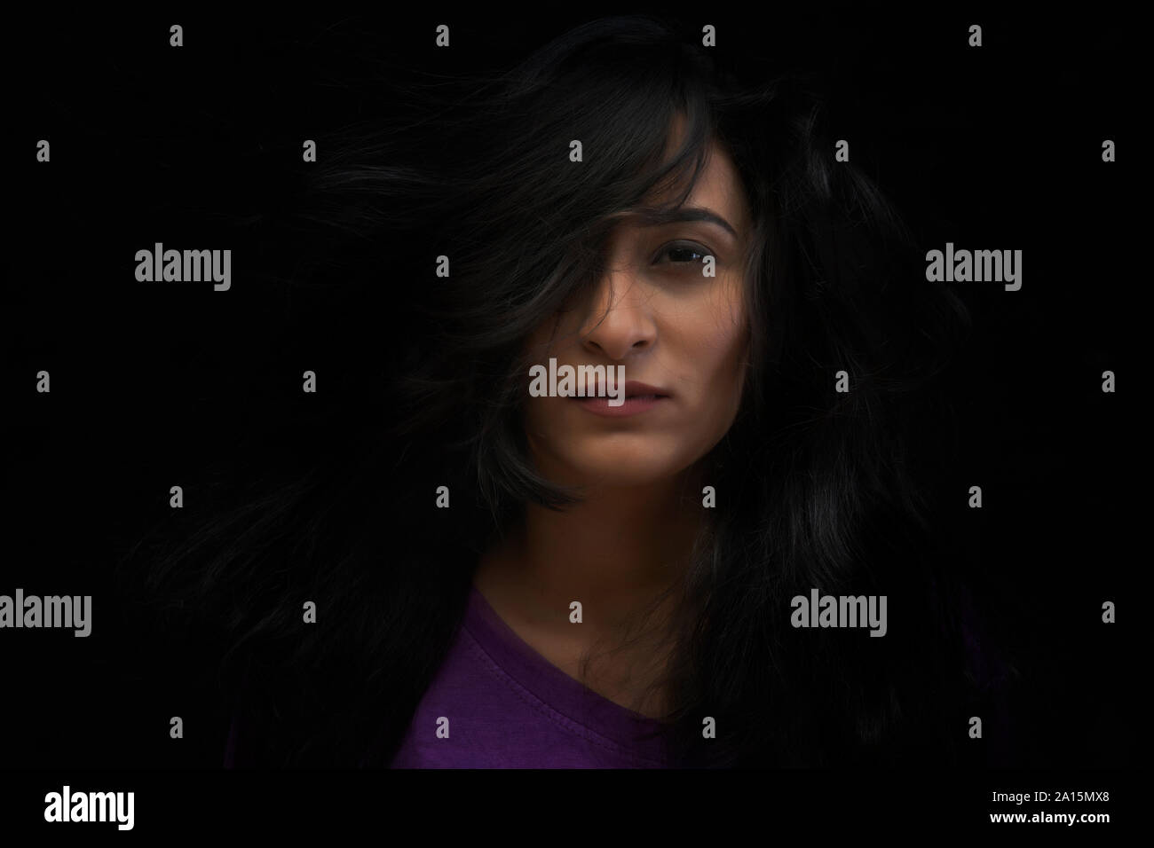 Portrait of young woman with dishevelled hair over black background Stock Photo