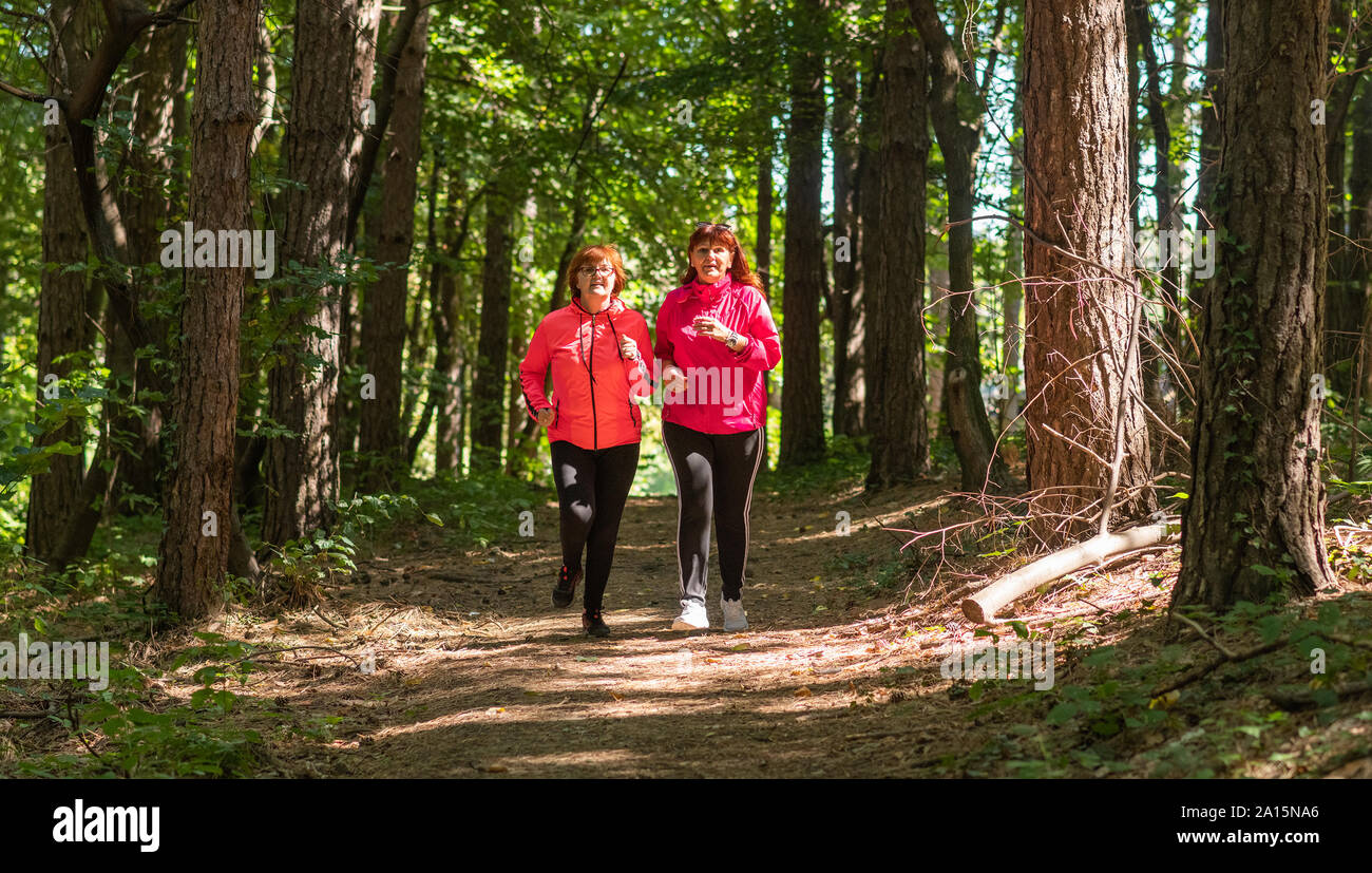 Two middle aged women running through a forest Stock Photo - Alamy