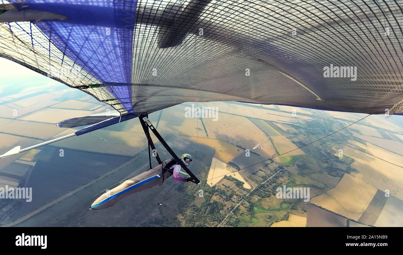 Two hang glider pilots soarabove terrain on high altitude. Extreme sports Stock Photo