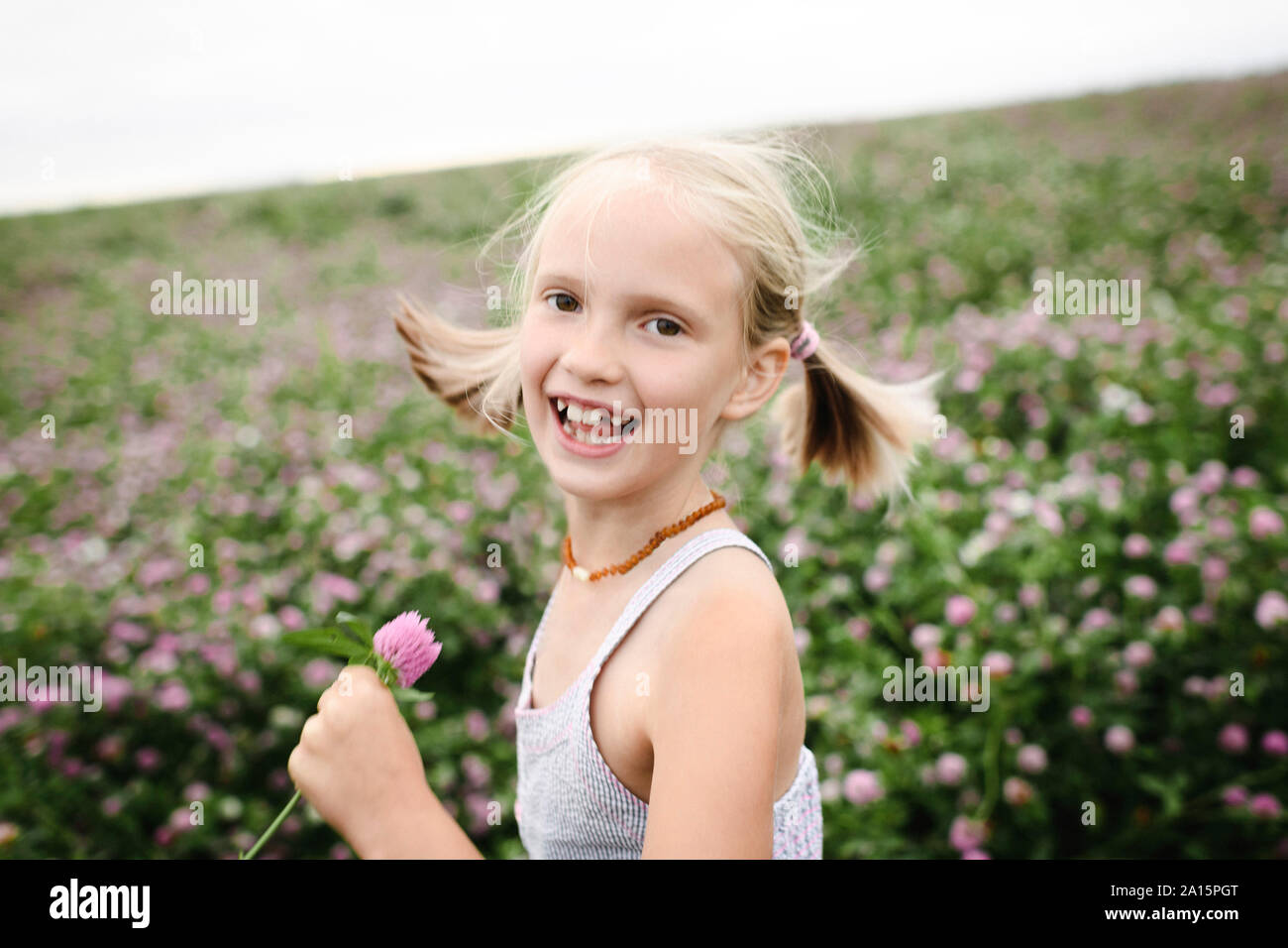 Laughing girl holding clover flowers Stock Photo