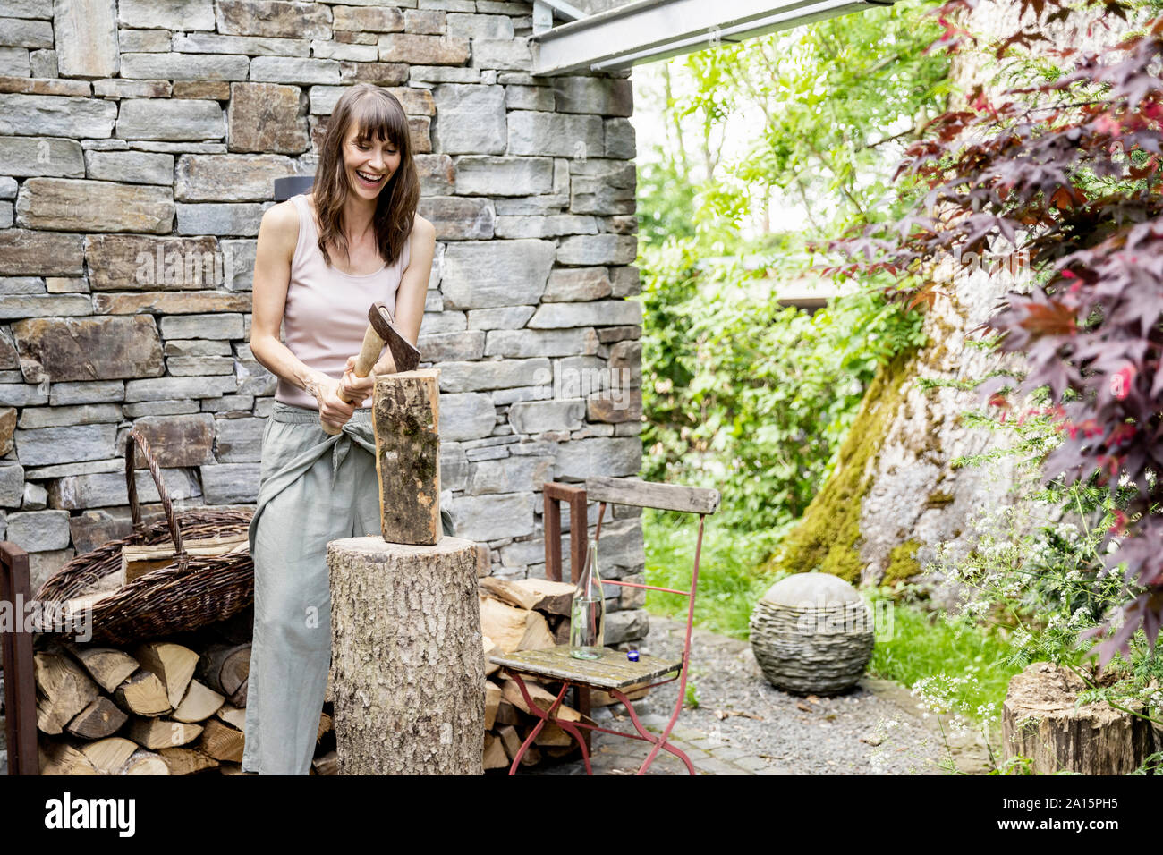 Screaming woman chopping wood in front of a house Stock Photo