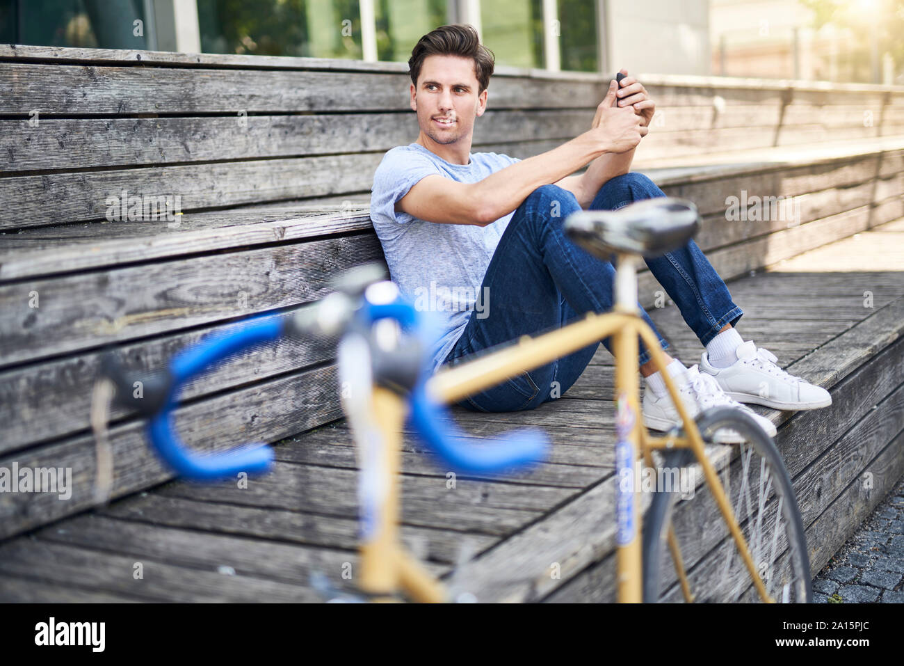 Portrait of man with racing bicycle sitting on bench having a rest Stock Photo