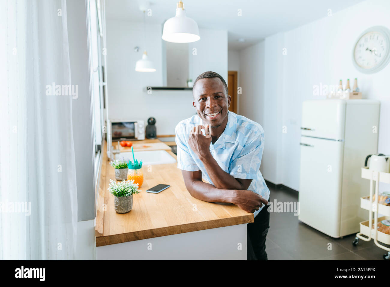 Portrait of smiling young man in kitchen at home Stock Photo
