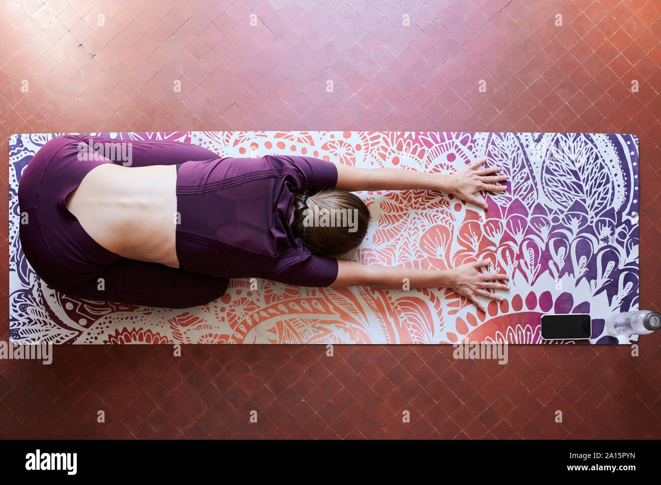 Young brunette woman practising yoga in student dorm, child position from above Stock Photo
