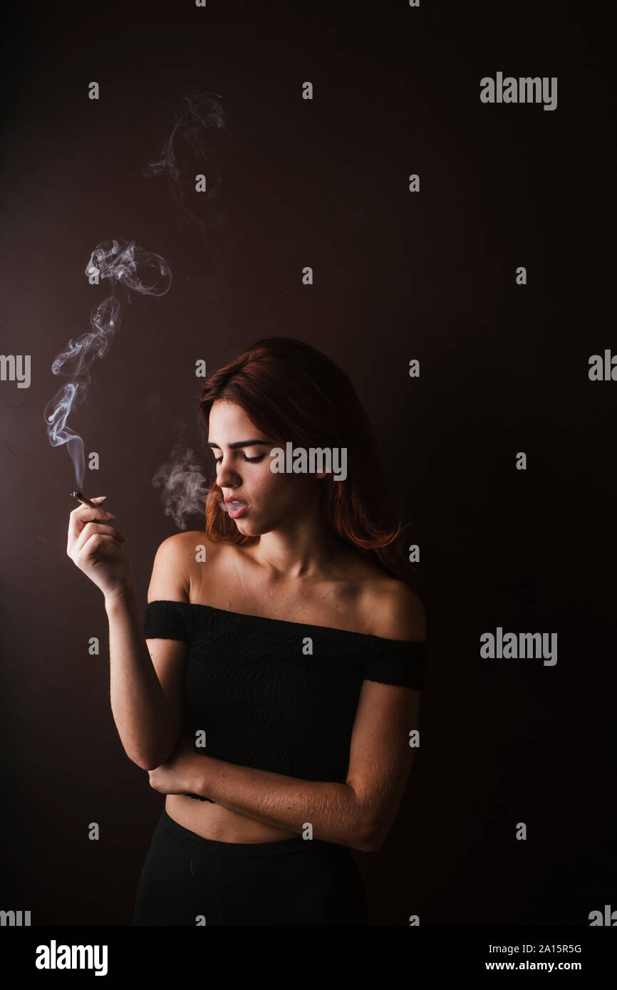 Relaxed young woman sitting smoking hires stock photography and images