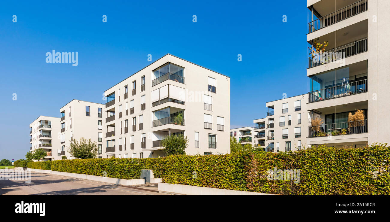 Hedge along sidewalk in front of residential buildings Stock Photo
