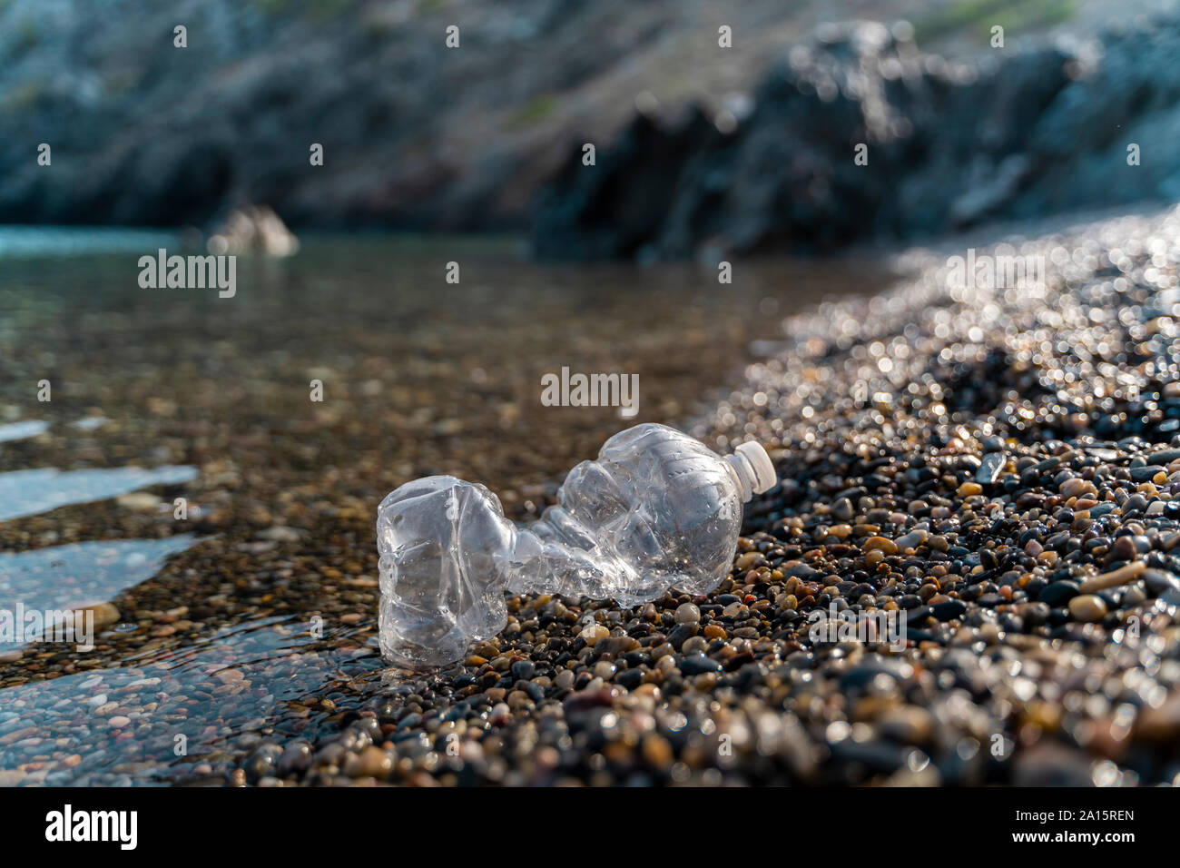 Empty plastic bottle lying on stony beach at seaside Stock Photo