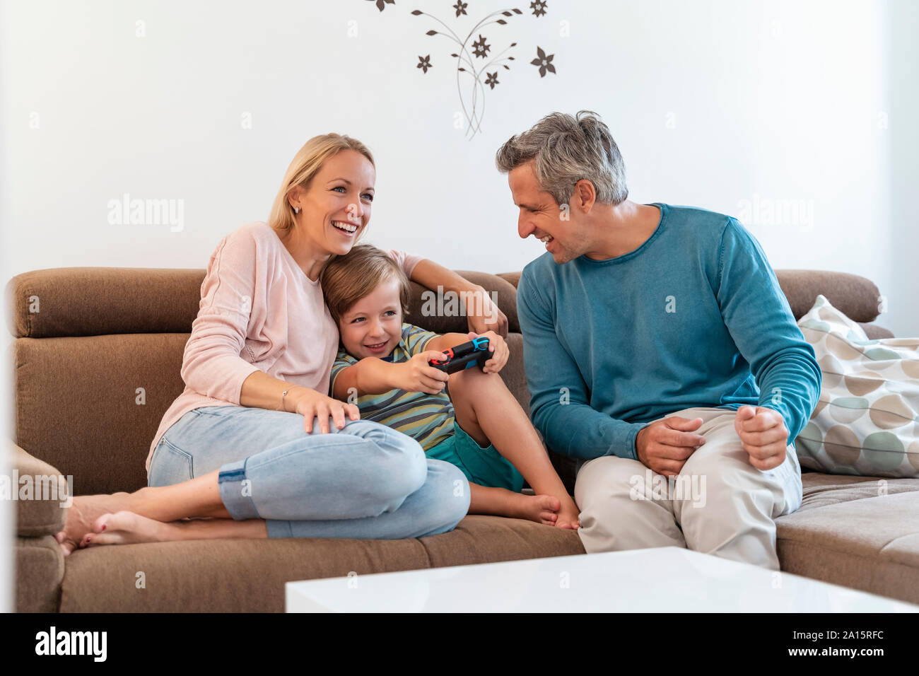 Happy parents with son playing video game on couch at home Stock Photo