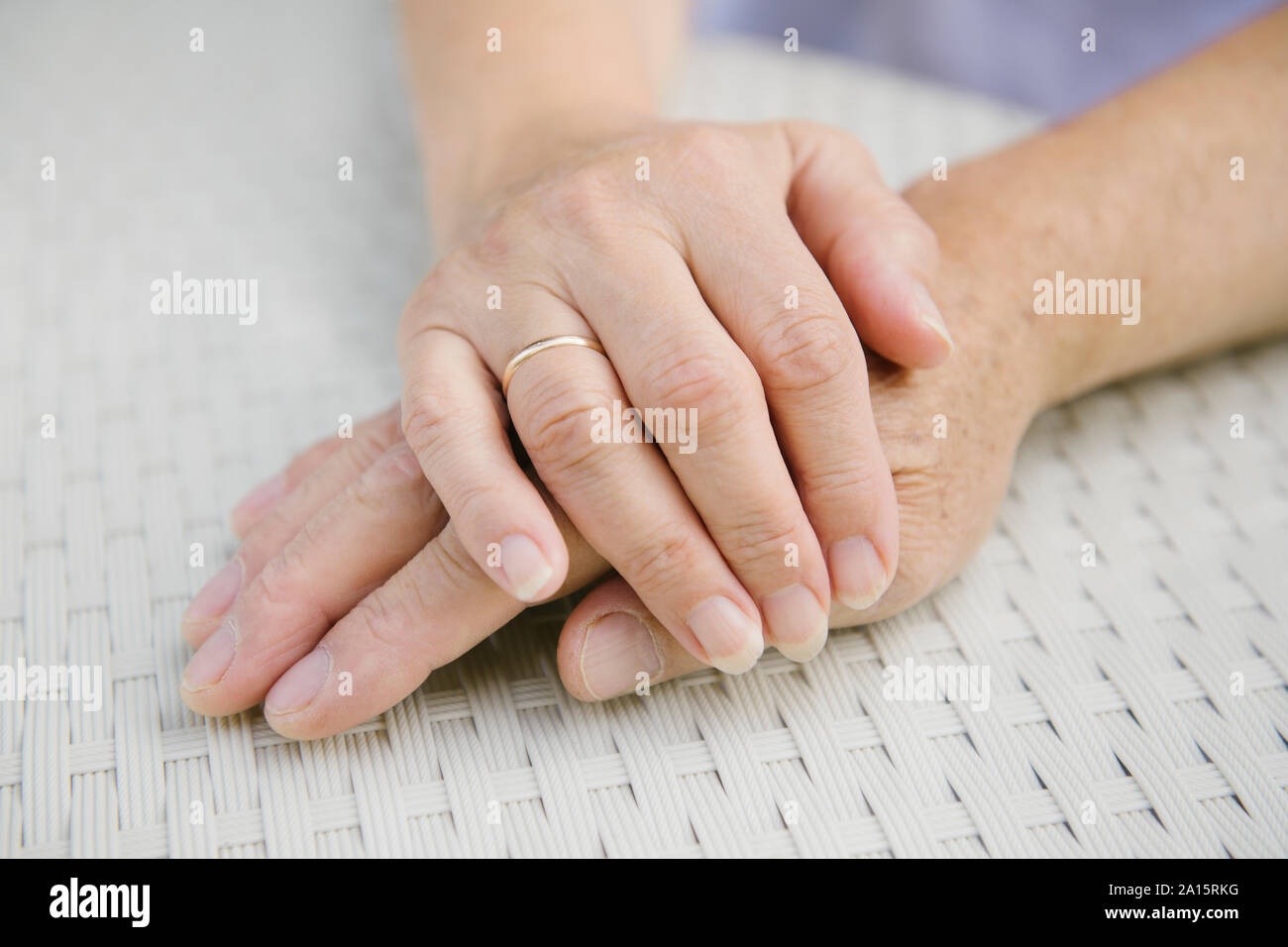 Senior couple sitting at garden table holding hands, close-up Stock Photo