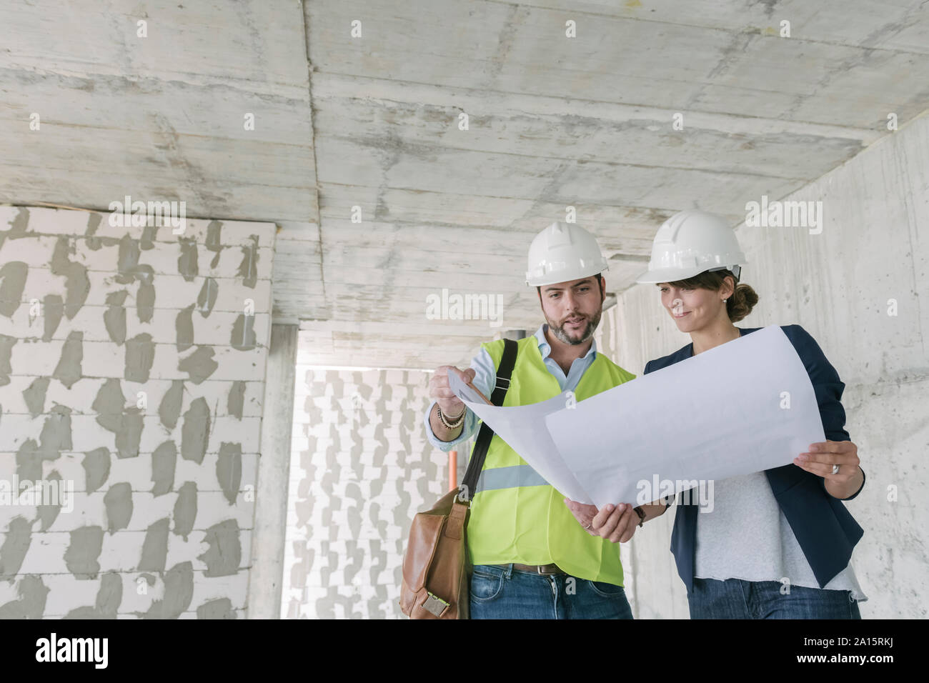 Architect and female manager talking about architectural plan at construction site Stock Photo
