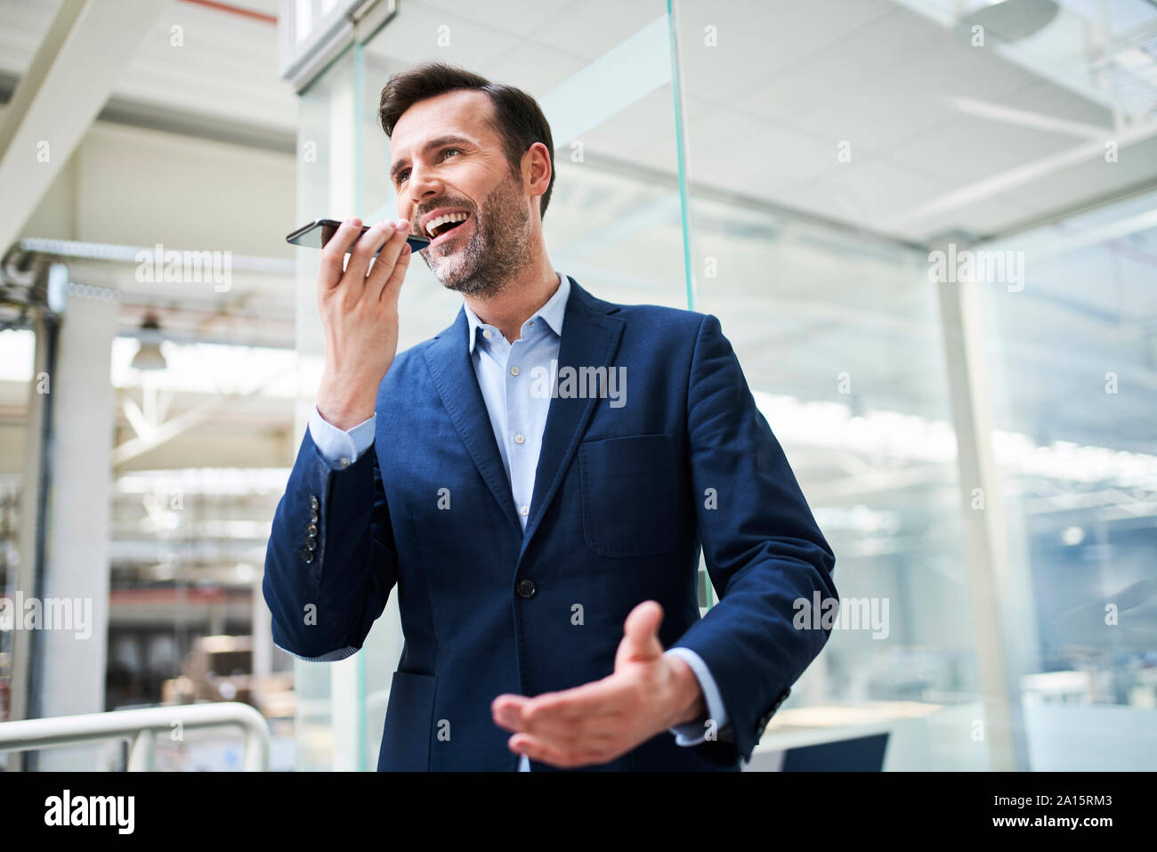 Happy businessman using cell phone in factory Stock Photo