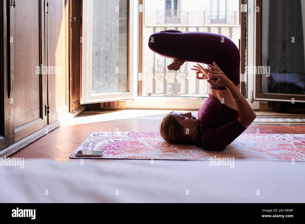 Young brunette woman practising yoga in student dorm Stock Photo