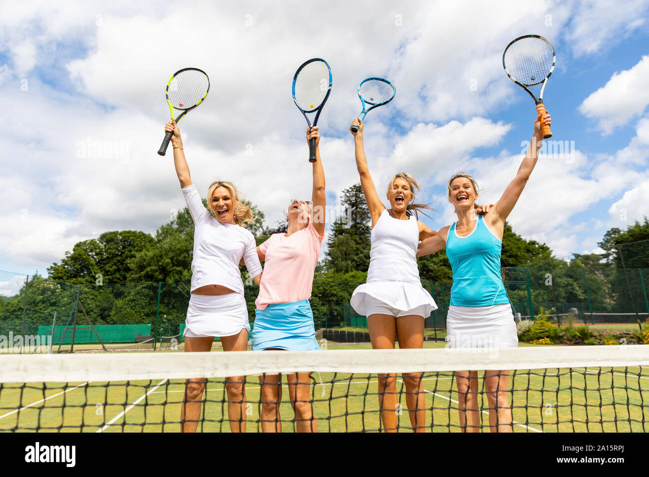 Happy female tennis players celebrating the victory on grass court Stock Photo