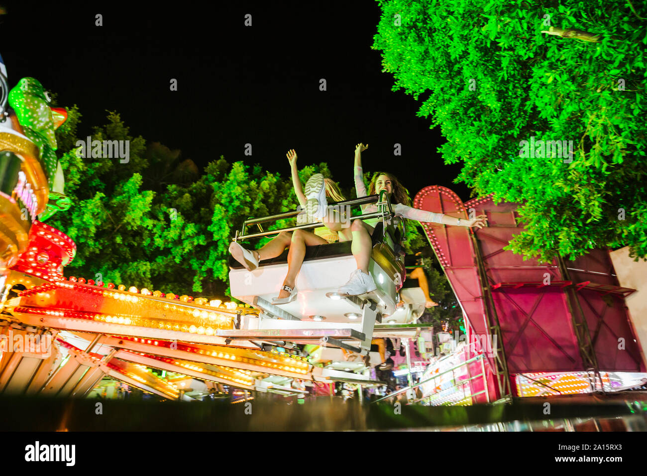 Two excited young women in a fairground ride on a funfair at night Stock Photo