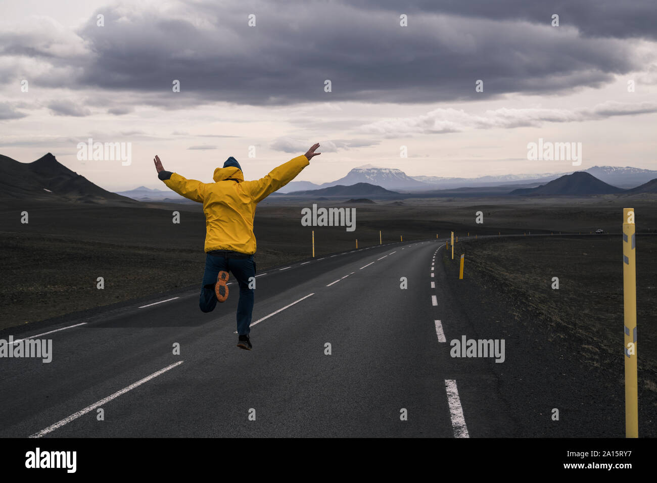 Happy man jumping for joy on an empty road, Iceland Stock Photo