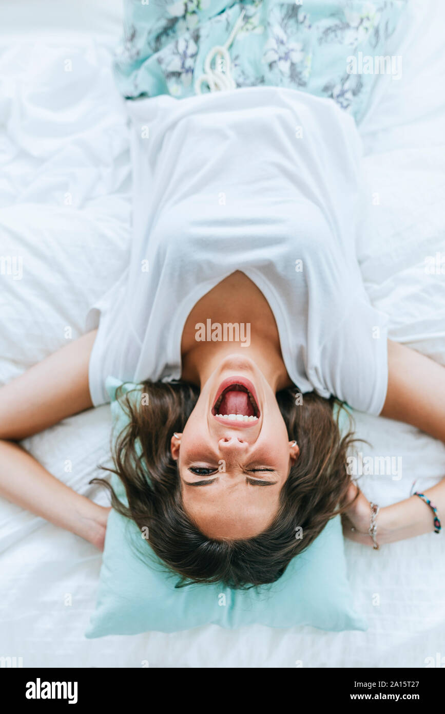 Top view of happy young woman lying in bed winking Stock Photo
