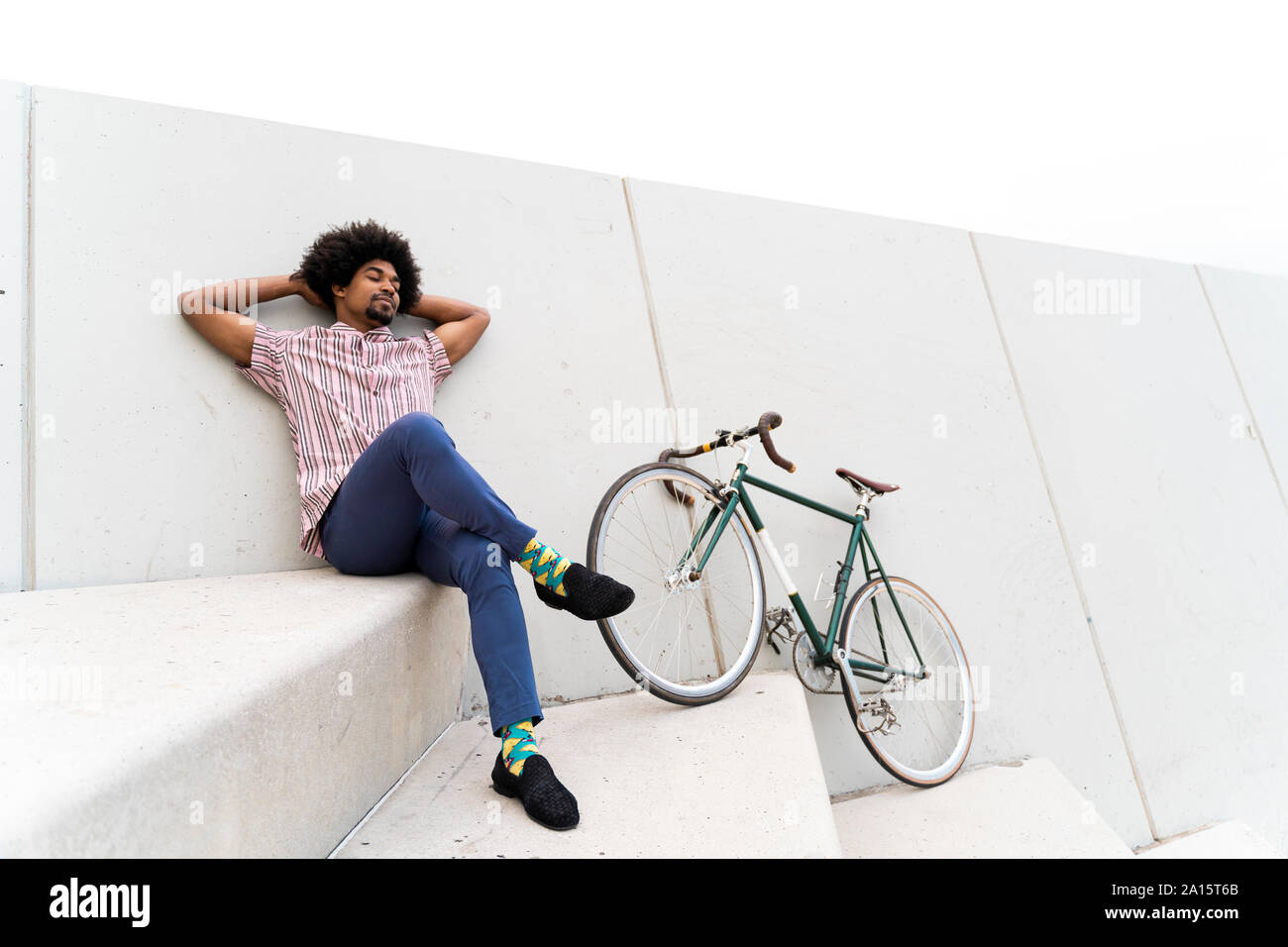 Young man during break leaning on a wall, bicycle Stock Photo