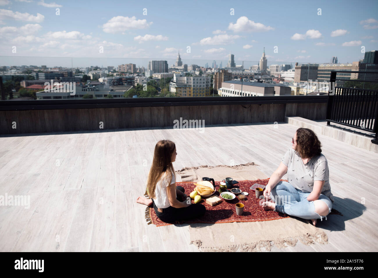 Woman with below-elbow amputation and girl having a healthy meal on the roof Stock Photo
