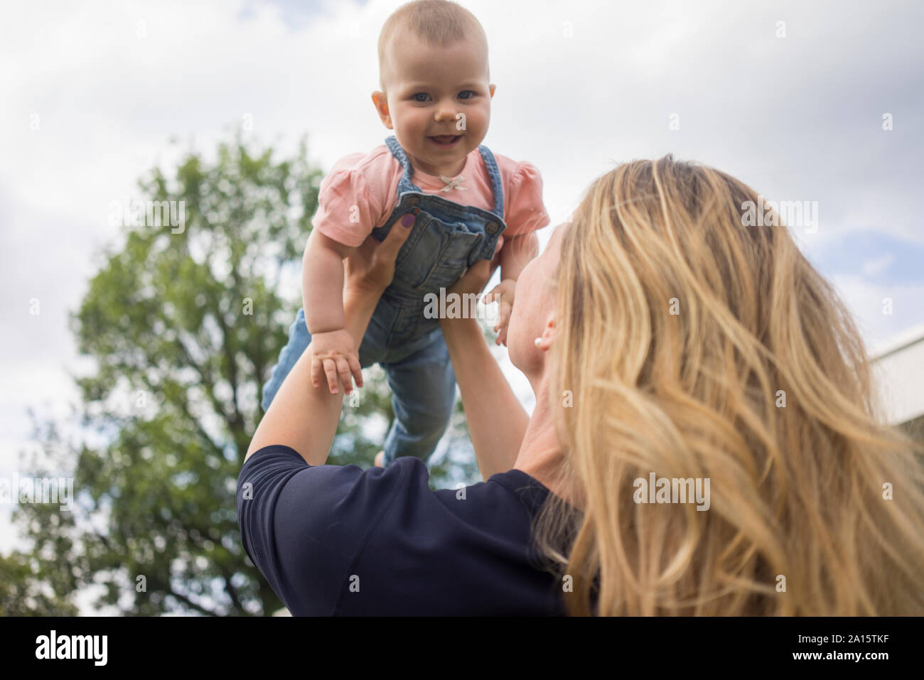 Happy mother lifting up baby girl outdoors Stock Photo