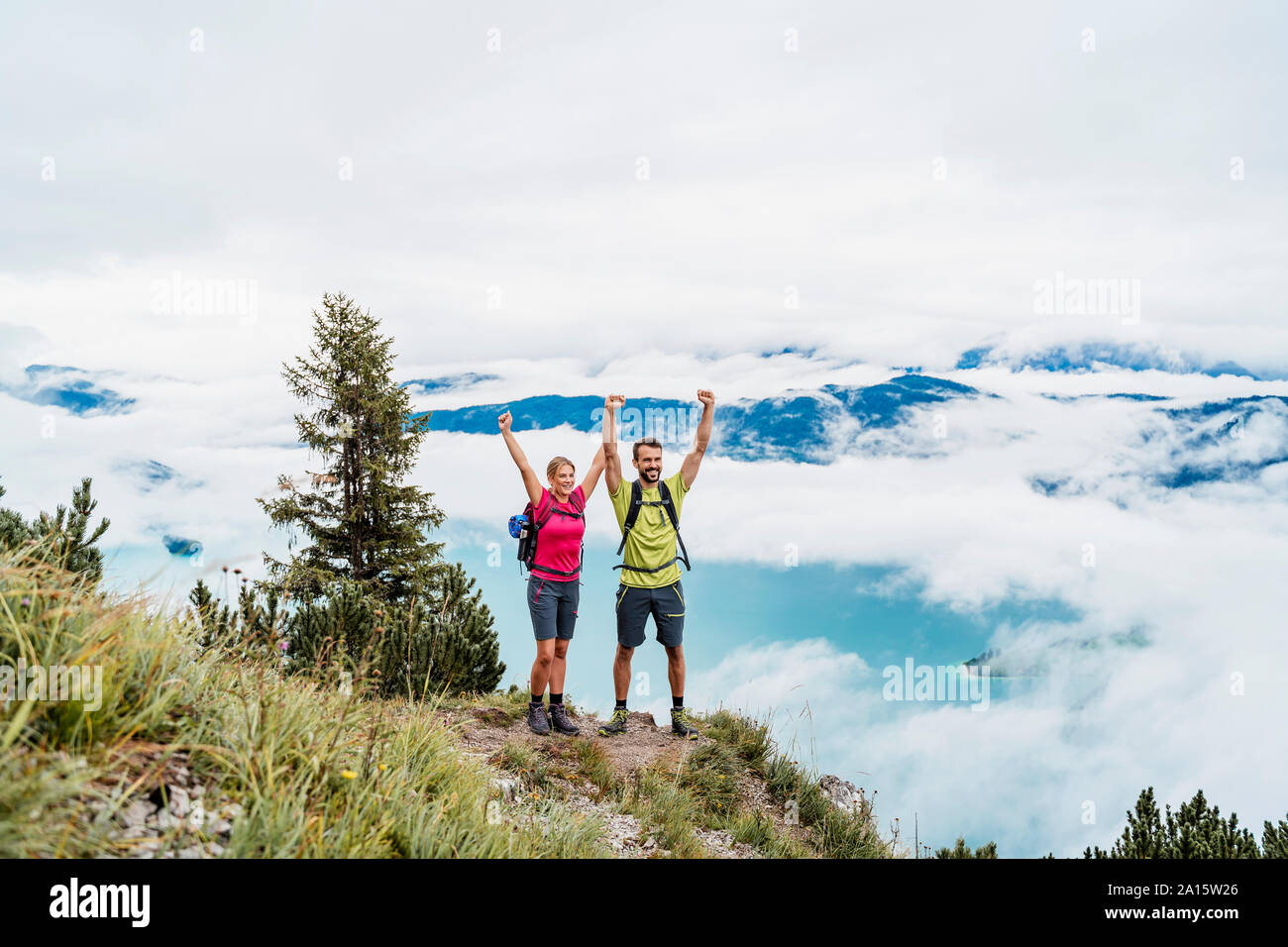 Happy young couple with raised arms on a hiking trip in the mountains, Herzogstand, Bavaria, Germany Stock Photo