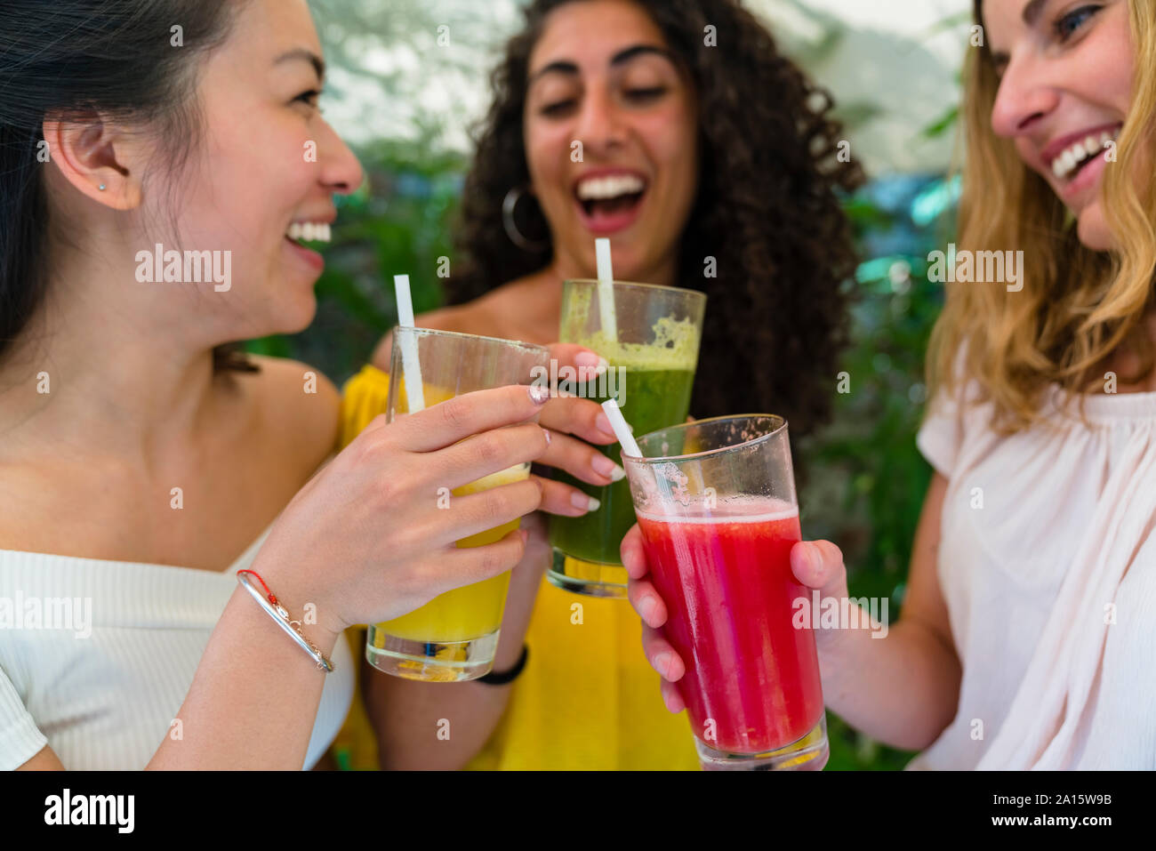 Three happy young women toasting with healthy drinks Stock Photo