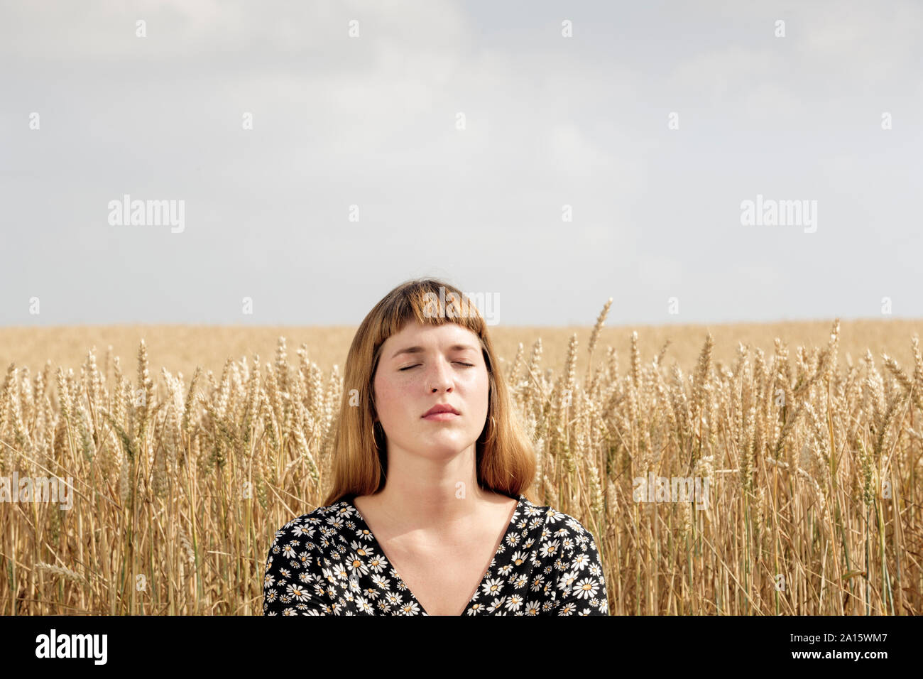 Portrait of young woman with eyes closed relaxing in front of grain ...