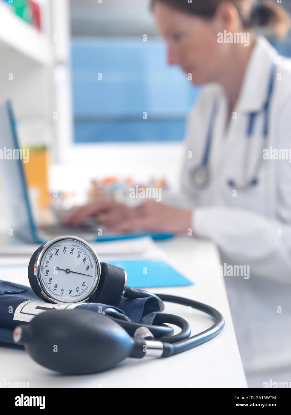 Health check, Doctor examining patients records after a consultation with the focus on a blood pressure gauge Stock Photo