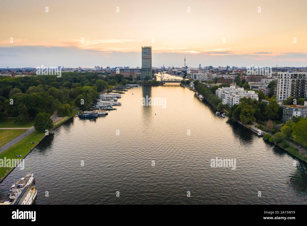 Spree river flowing amidst residential building seen from Treptower Park against sky during sunset Stock Photo