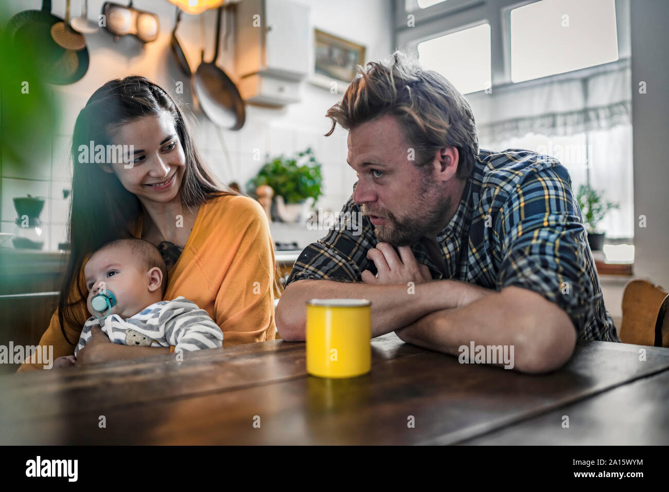 Family with baby sitting at kitchen table at home Stock Photo