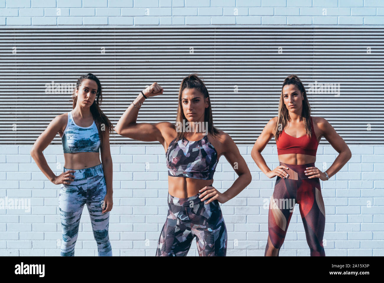 Portrait of confident young woman with friends  flexing muscles Stock Photo