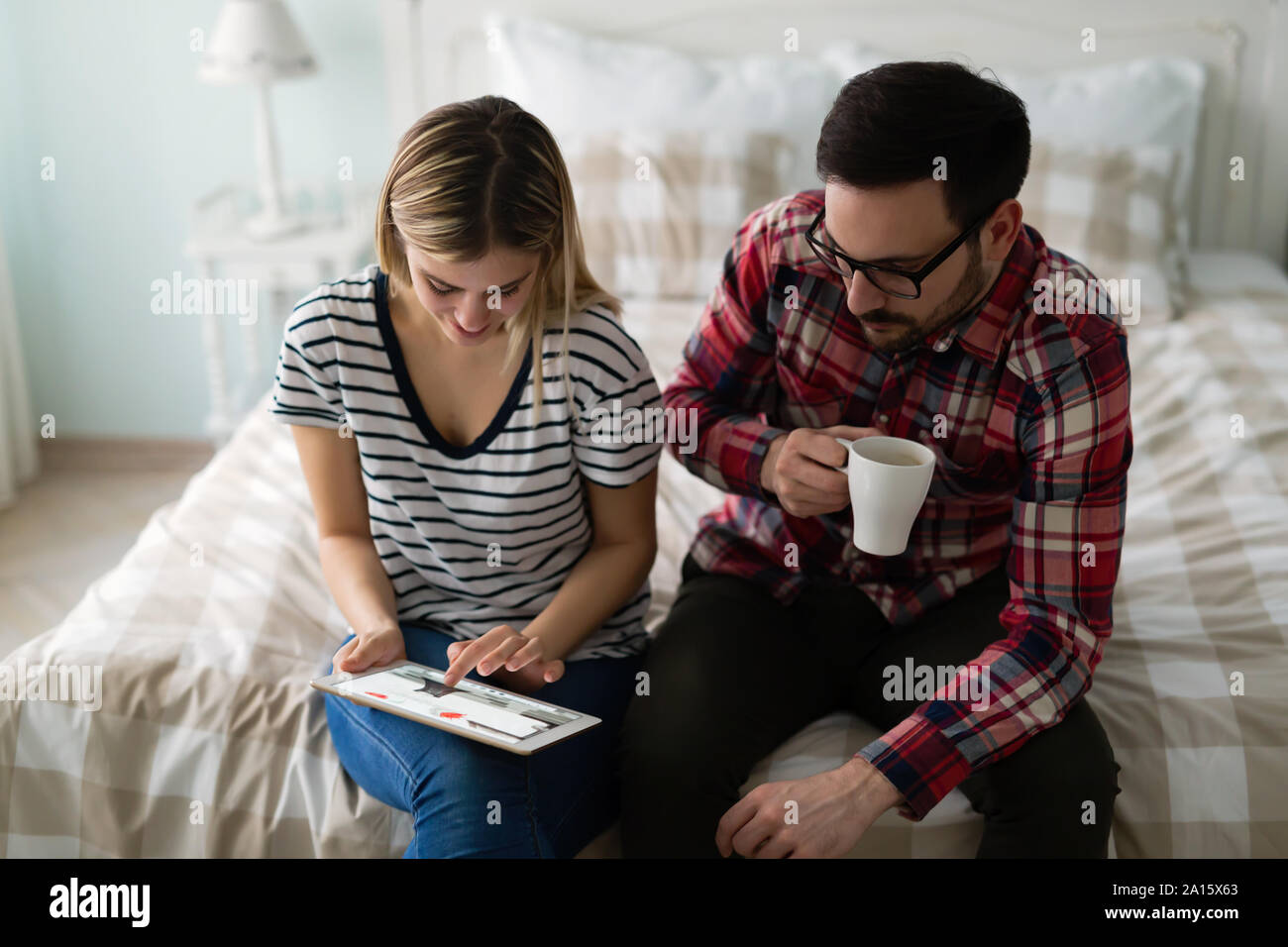 Young attractive couple using tablet in bedroom Stock Photo