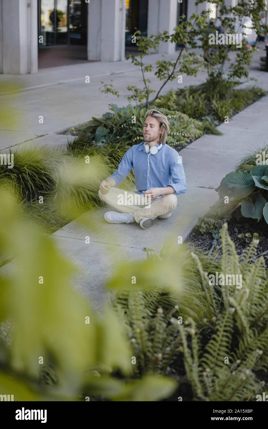 Young man meditating outside office building Stock Photo