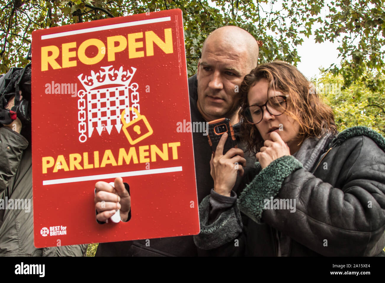 London, UK. 24th Sep, 2019. A couple listen on a phone for the ruling as crowds gathered outside The Supreme Court to hear the ruling that the Boris Johnson's Government acted unlawful in their proroguation of Parliament. Credit: David Rowe/Alamy Live News Stock Photo