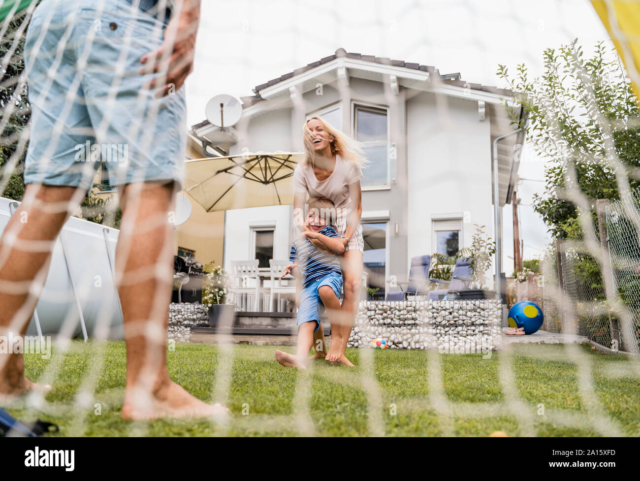 Happy family playing football in garden Stock Photo