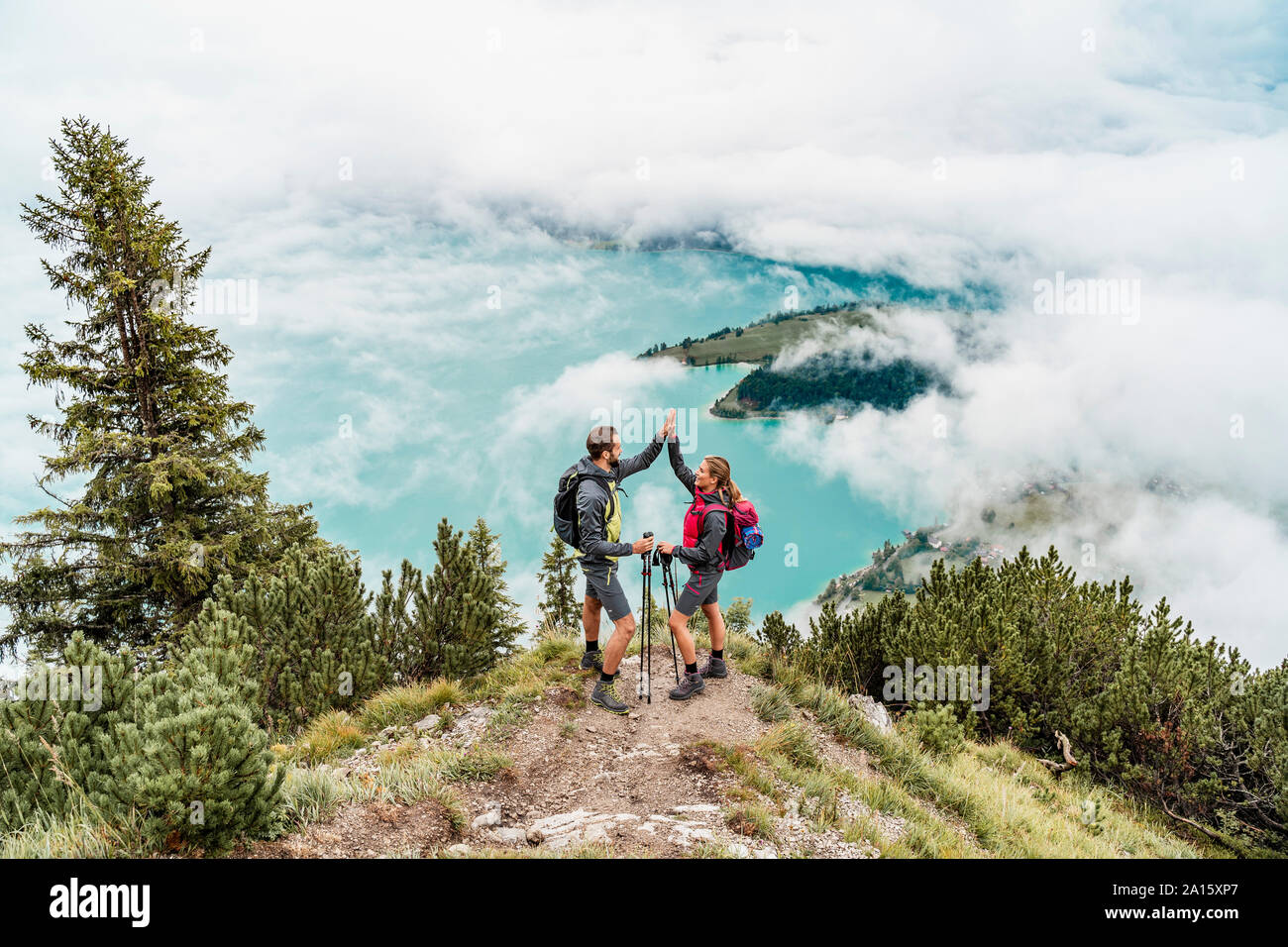 Happy young couple on a hiking trip in the mountains high fiving, Herzogstand, Bavaria, Germany Stock Photo