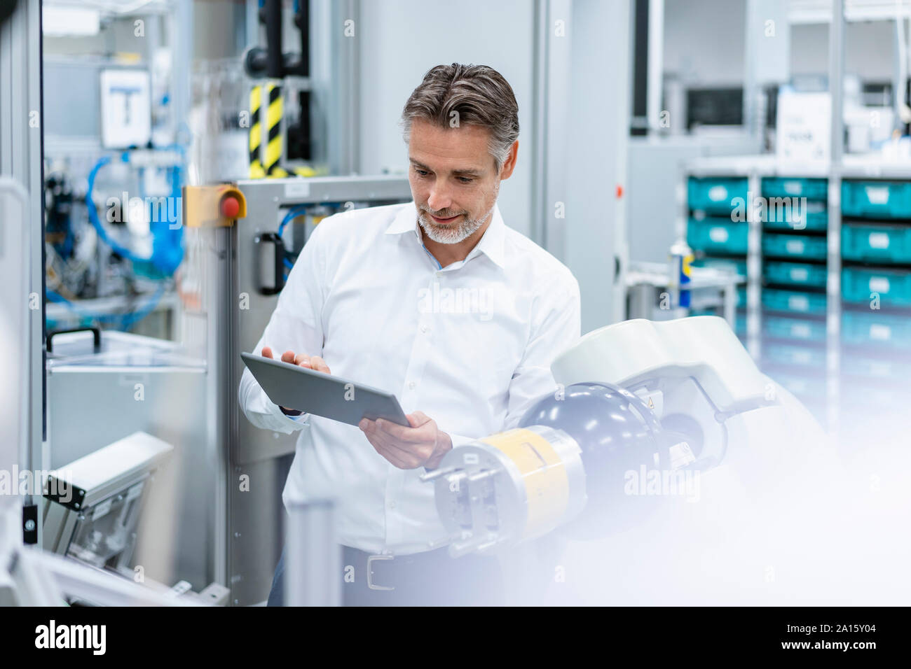 Businessman with tablet at assembly robot in a factory Stock Photo
