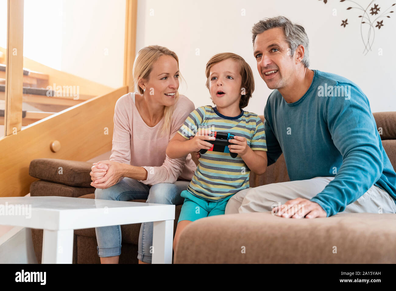 Happy parents with son playing video game on couch at home Stock Photo