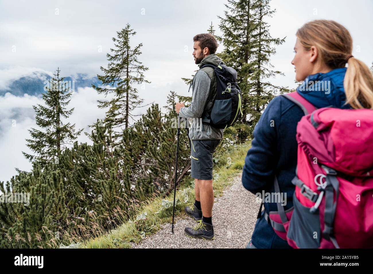 Young couple on a hiking trip in the mountains looking at view, Herzogstand, Bavaria, Germany Stock Photo