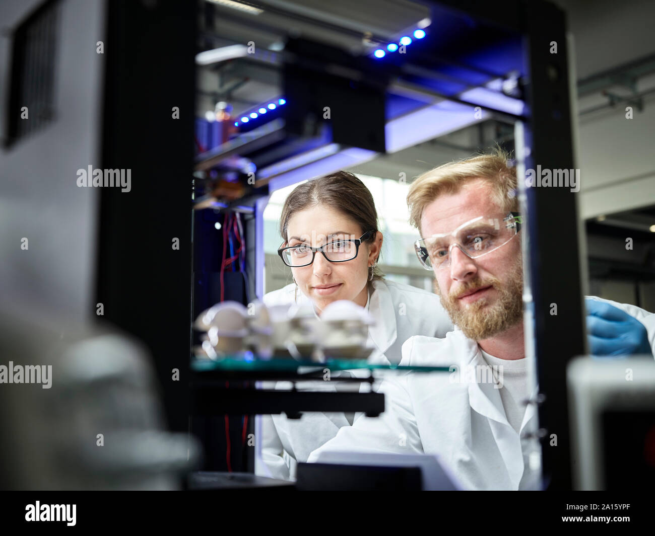 Two technicians looking at turbine wheel being printed in 3d printer Stock Photo
