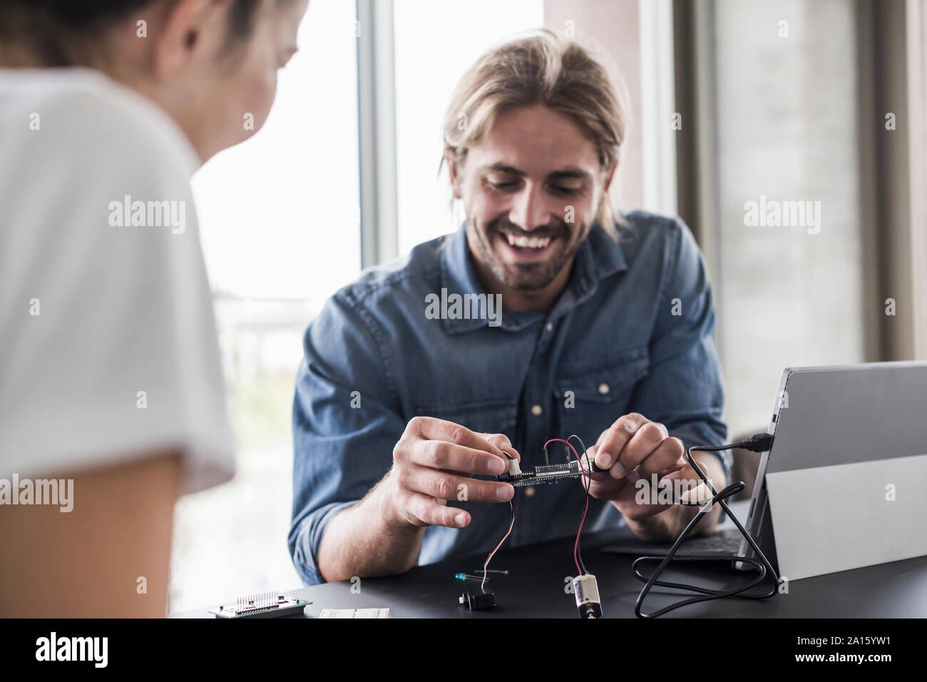 Smiling young man and woman working on computer equipment in office Stock Photo