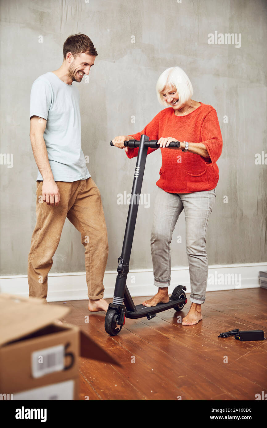 Senior woman trying out her new e-scooter, garndson assisting Stock Photo