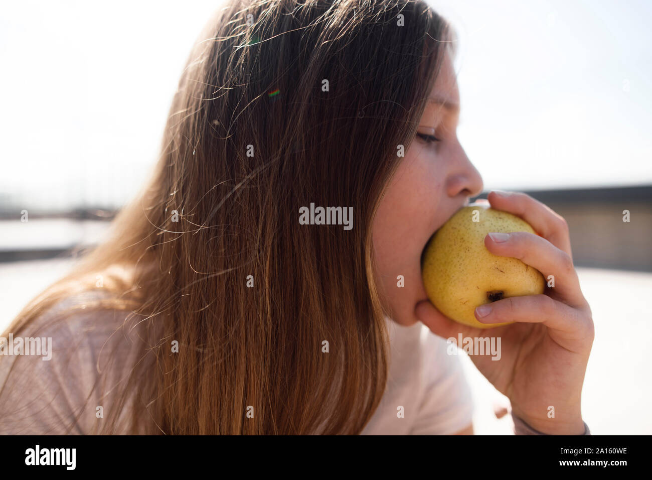 Girl eating an apple outdoors Stock Photo