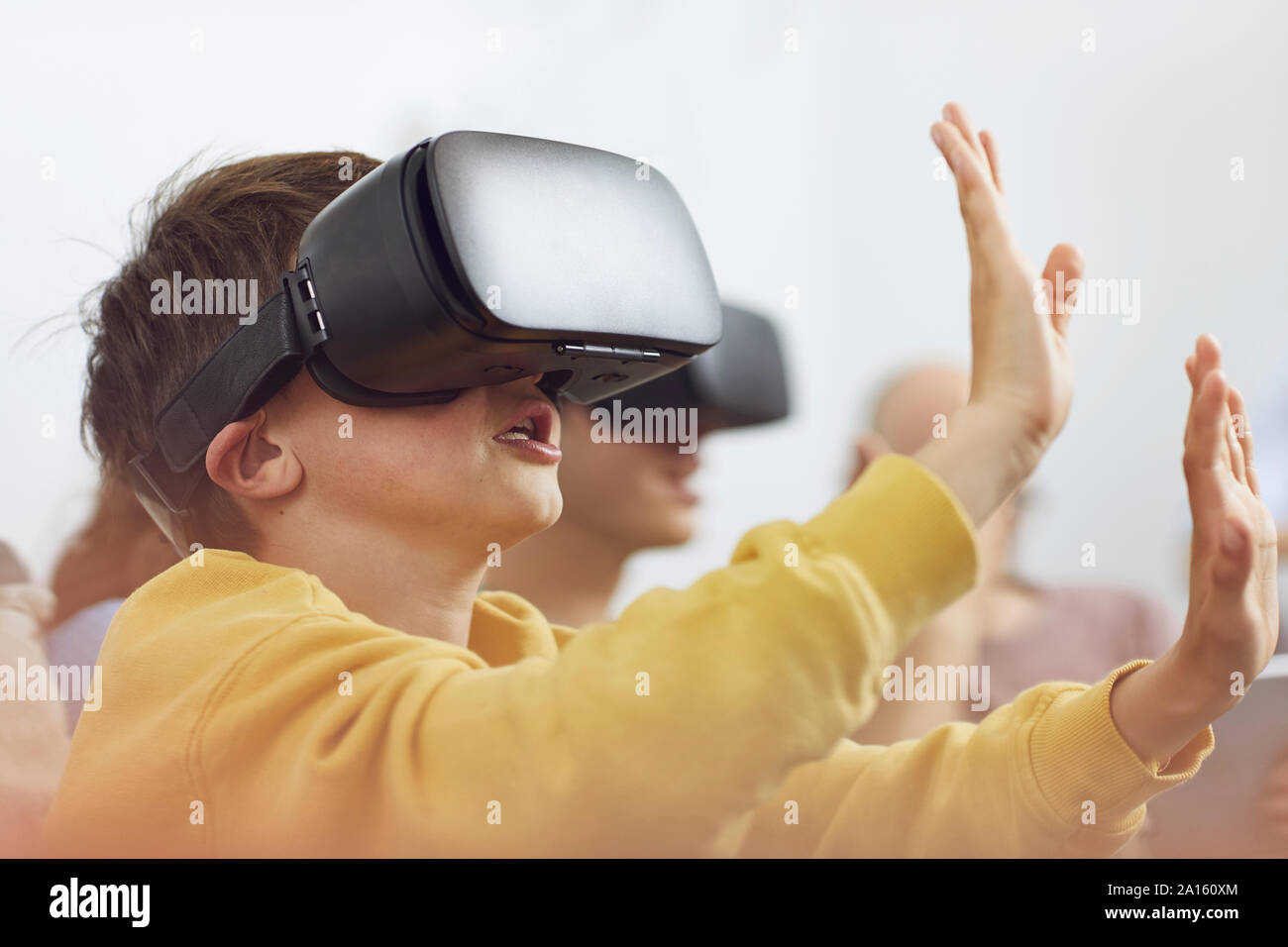 Little boy playing with VR goggles, sittiing on couch with his family Stock Photo