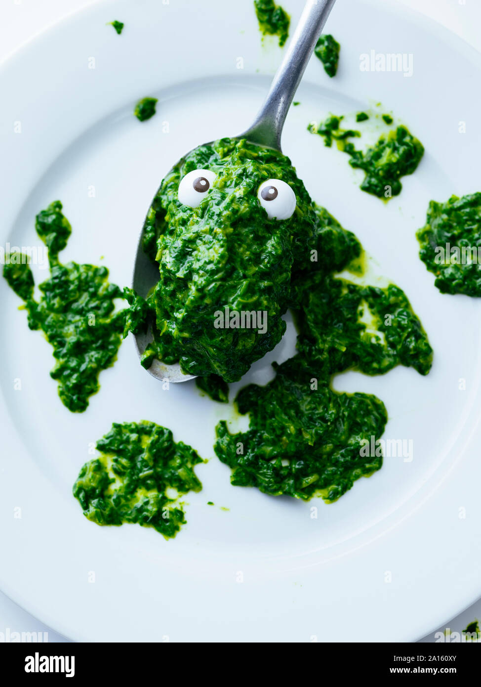 Spinach blob with artificial eyes on spoon Stock Photo