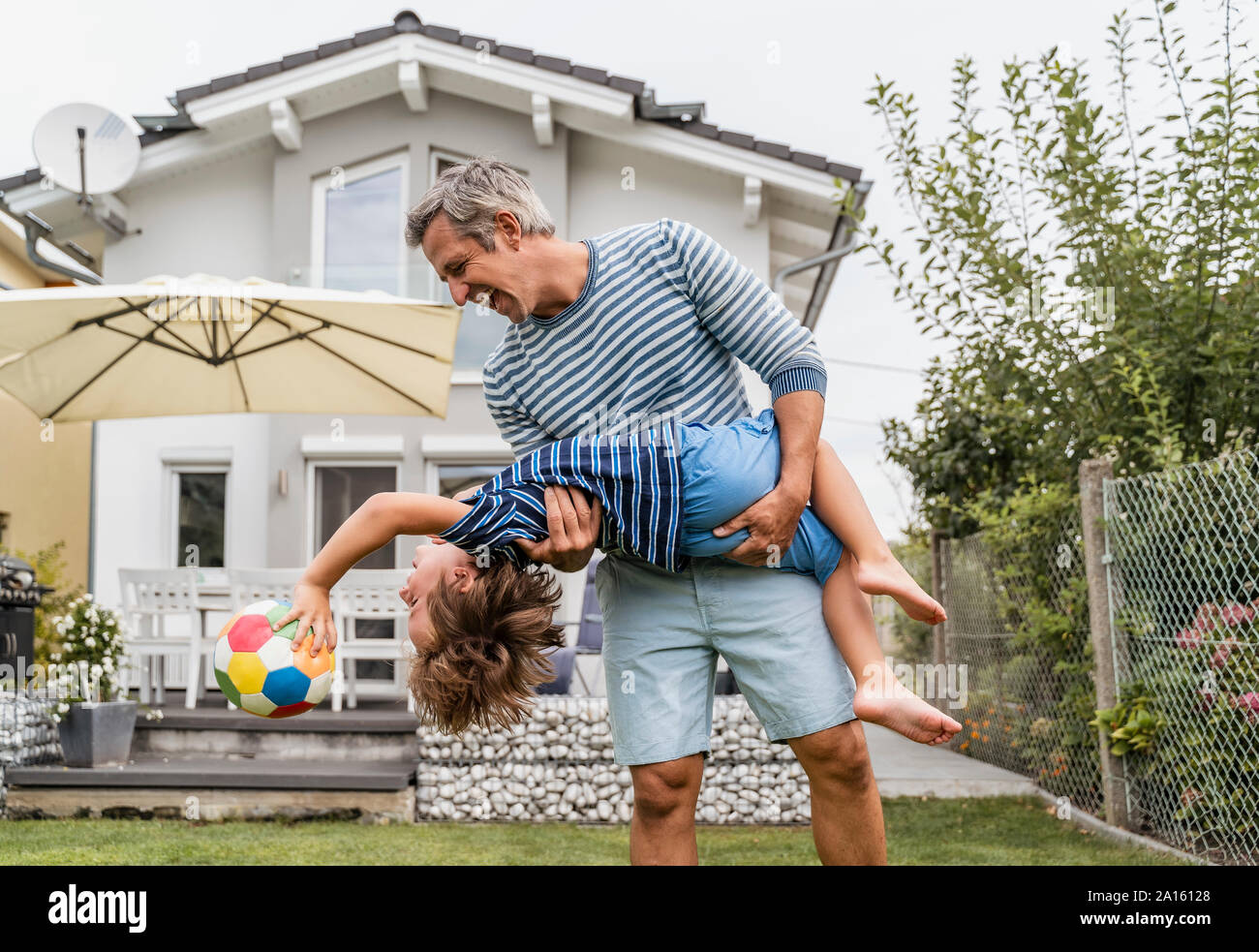 Playful father and son with football in garden Stock Photo