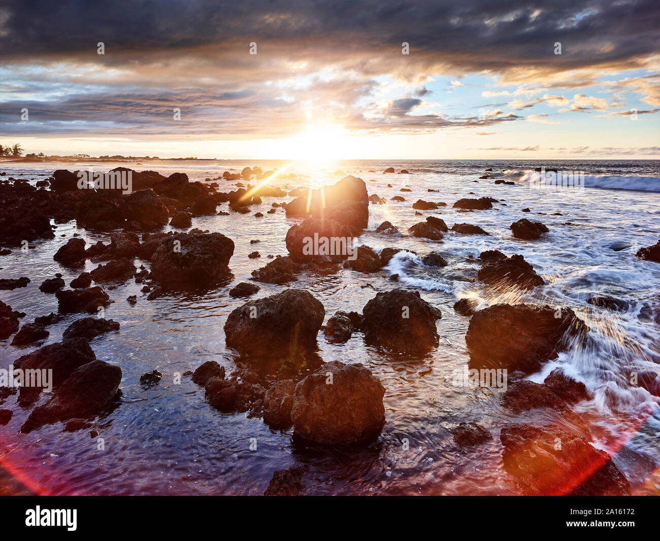 Volcanic rocks in Makalawena Bay against sky during sunset Stock Photo