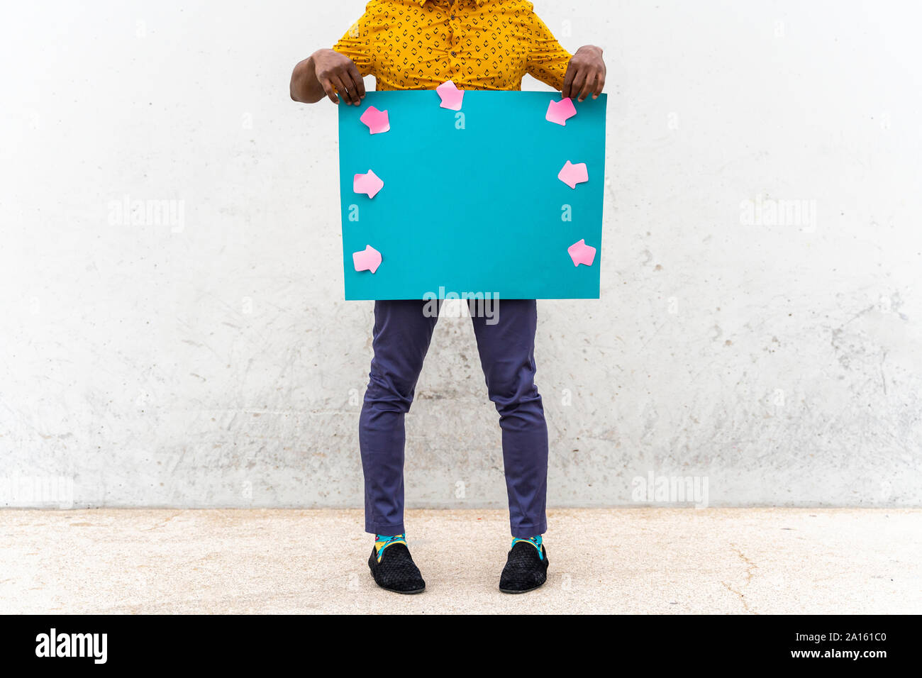 Young man wearing yellow shirt, blue indicating label with arrow signs Stock Photo