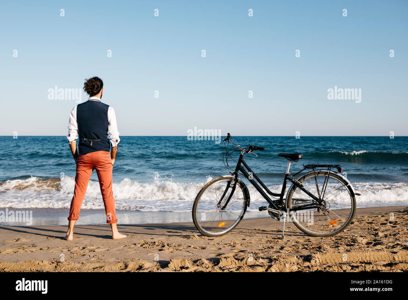 Well dressed man with his bike standing on a beach Stock Photo
